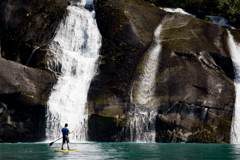 A guest explores Cascade Falls by standup paddle board in Tracy Arm, Alaska