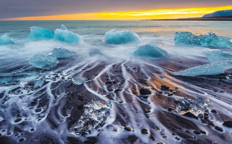 Icebergs Floating on a icy beach at Sunrise, South Iceland
