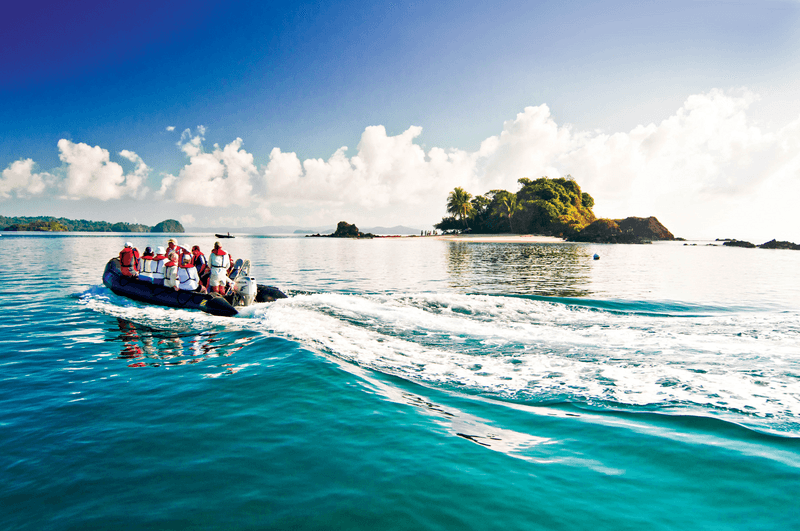 Guests from Lindblad Expedition ships tours on a zodiac to explore diverse habitats  like mangrove-lined beaches and islands