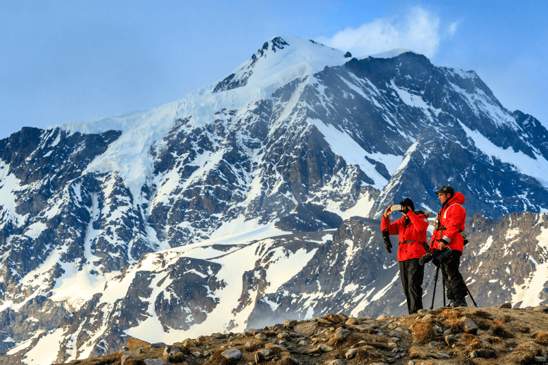 Guests taking photography with a mountain backdrop on St. Andrews Bay, South Georgia