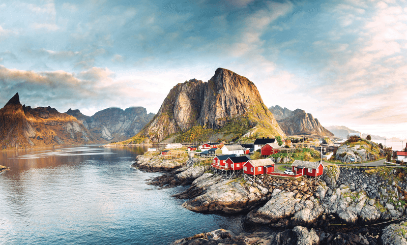 Dramatic sunset clouds moving over steep mountain peaks of a Norwegian fishing village at the Lofoten Islands in Norway