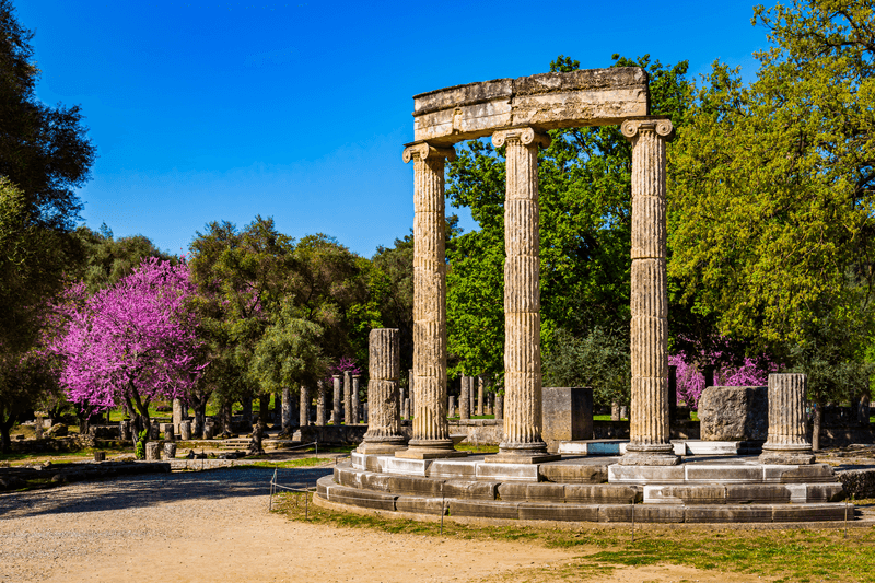 The ruins of Ancient Olympia with blooming cercis tree. Greece.