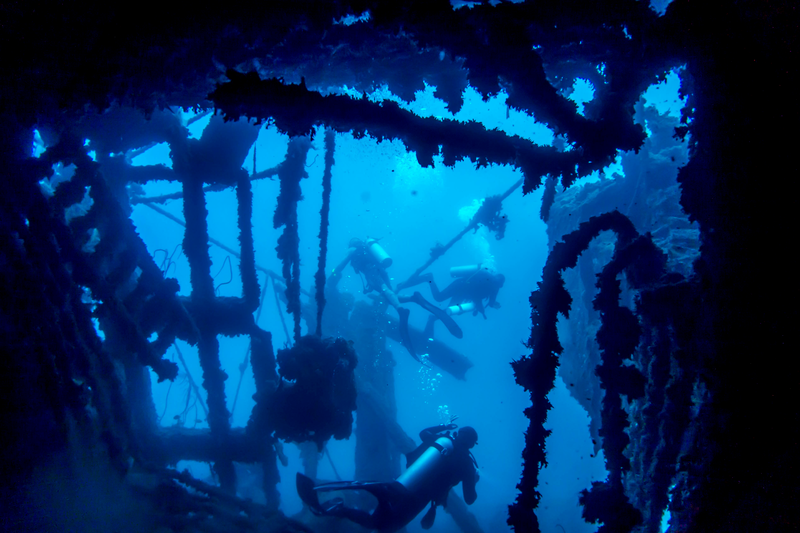 Scuba divers passing through the inside of a large coolidge shipwreck in Vanuatu
