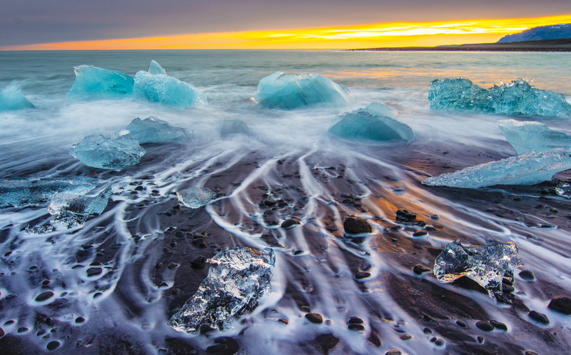 Icebergs Floating on a icy beach at Sunrise, South Iceland