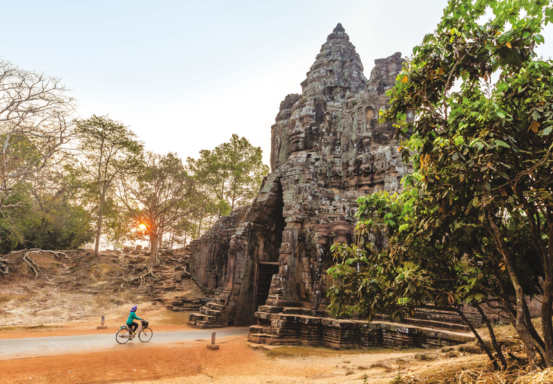 A guest bicycles through the South Gate in Angkor Thom at sunrise, Angkor, Siem Reap Province, Cambodia