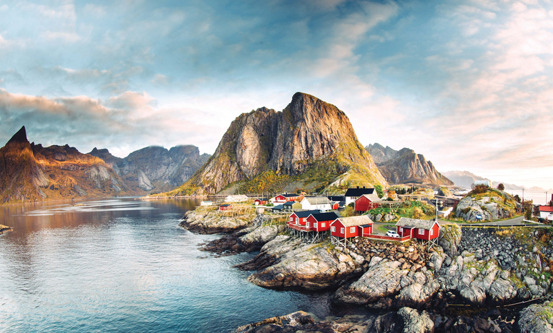 Dramatic sunset clouds moving over steep mountain peaks of a Norwegian fishing village at the Lofoten Islands in Norway