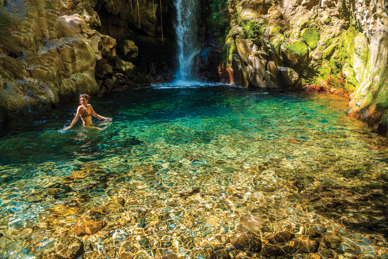 A guest enjoying a refreshing swim in the turqoise pool of Oropendola waterfall, Rincón de la Vieja.. Guanacaste, Costa Rica.