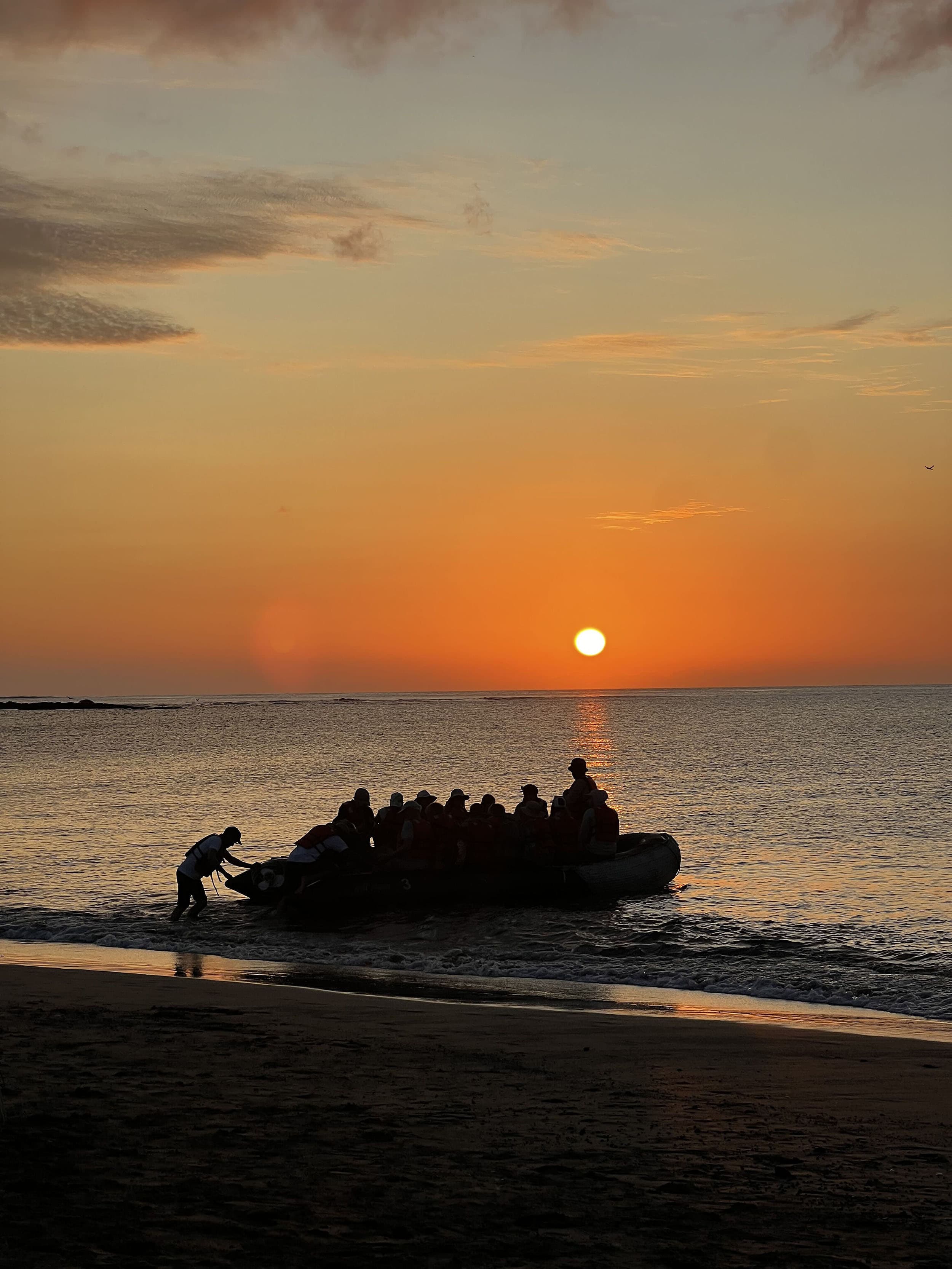 a zodiac on a beach at sunset