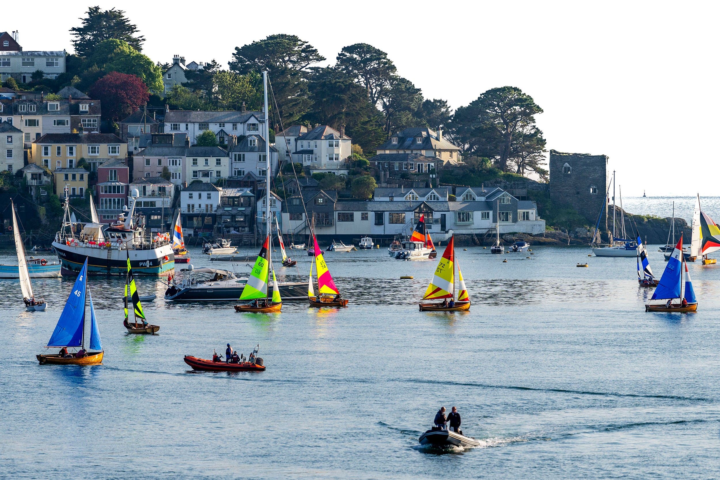 colorful sailboats in the harbor next to a seaside town