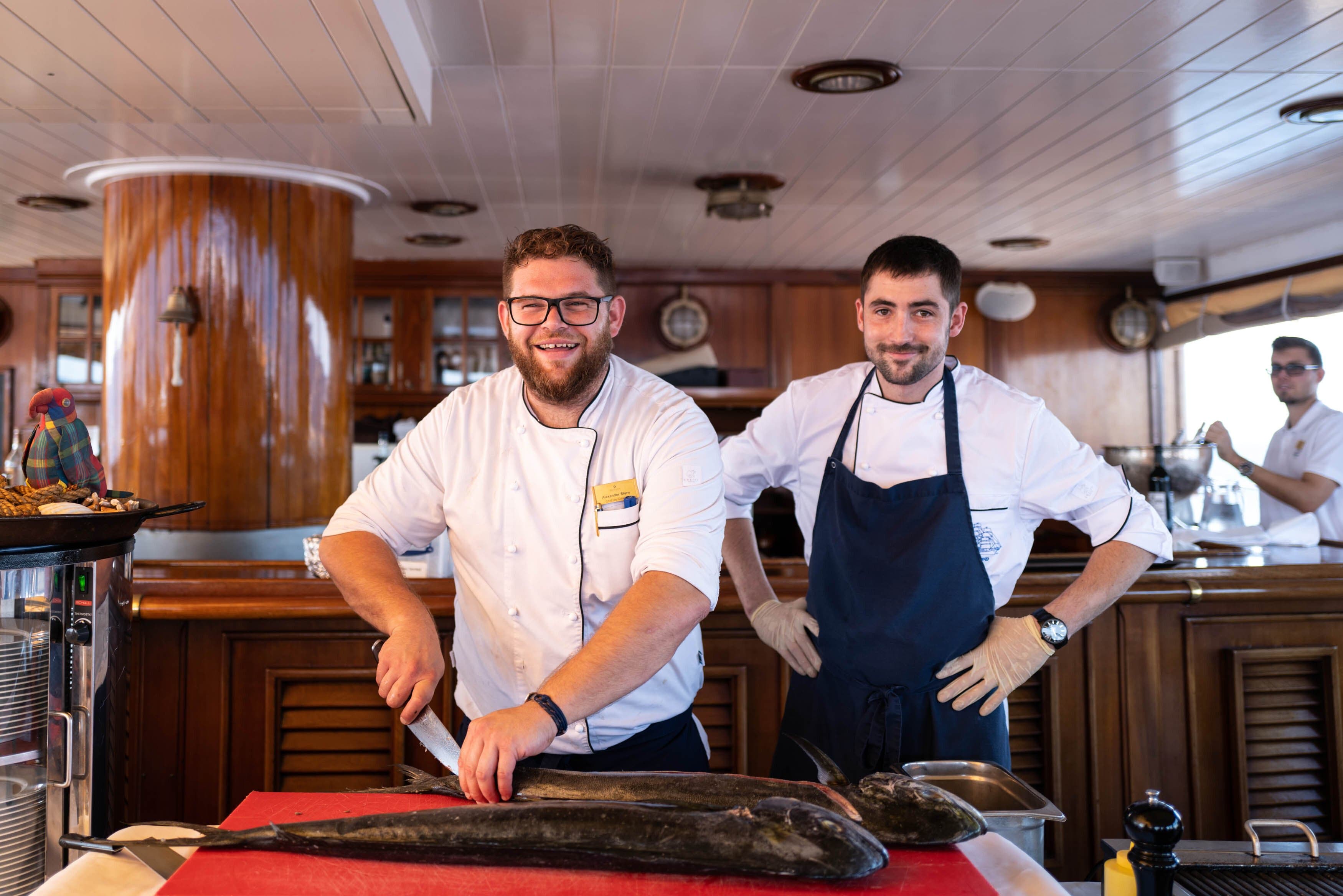Two chefs filet a fish in the galley on the Sea Cloud II