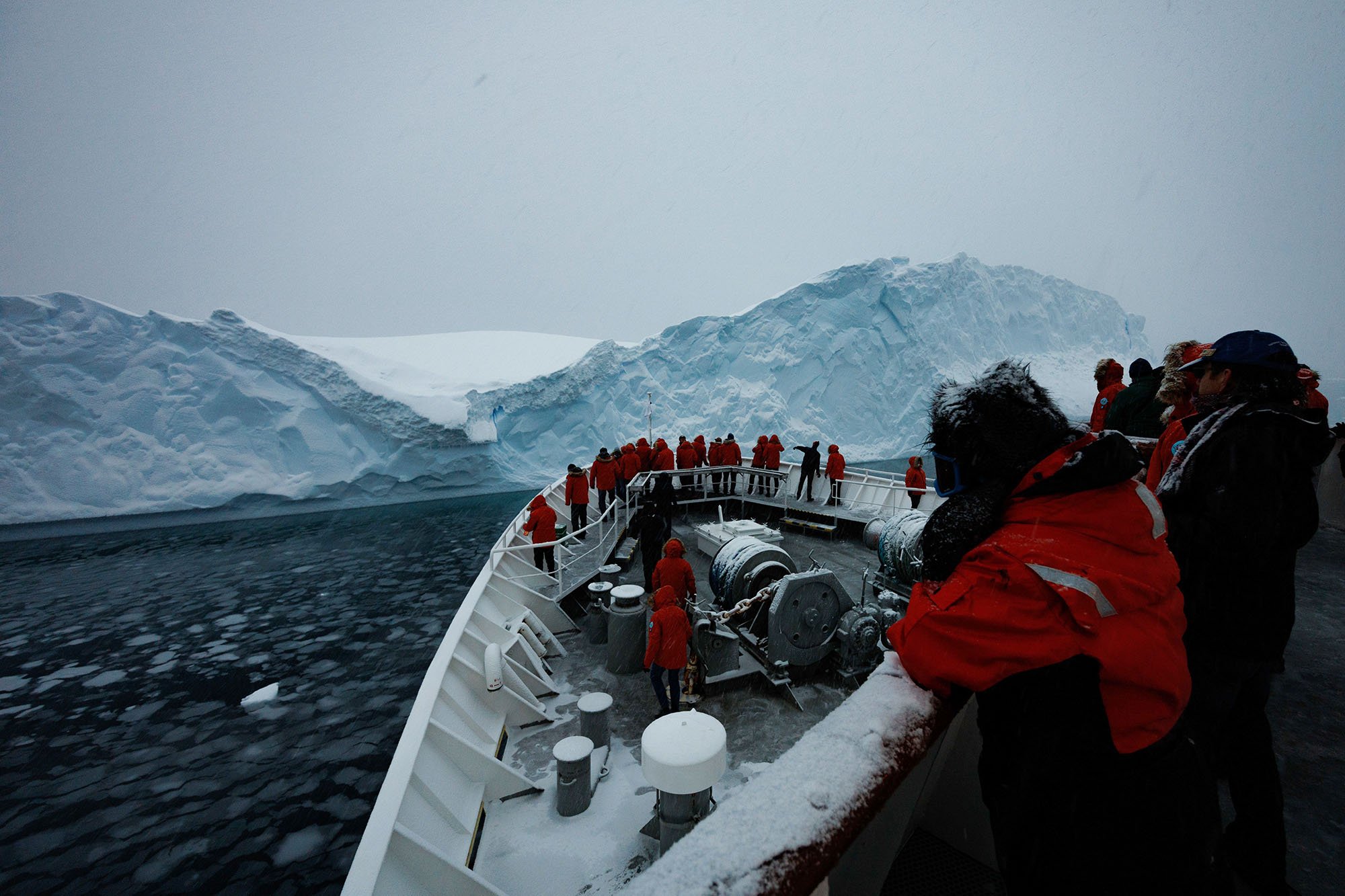 red-parka-wearing people on the bow of a ship