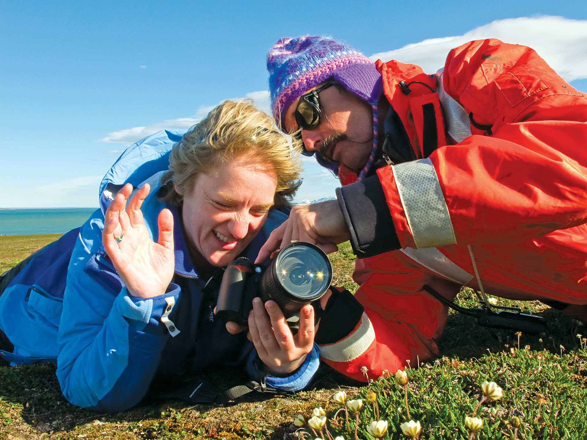 Two people take photos of the plant life in Svalbard