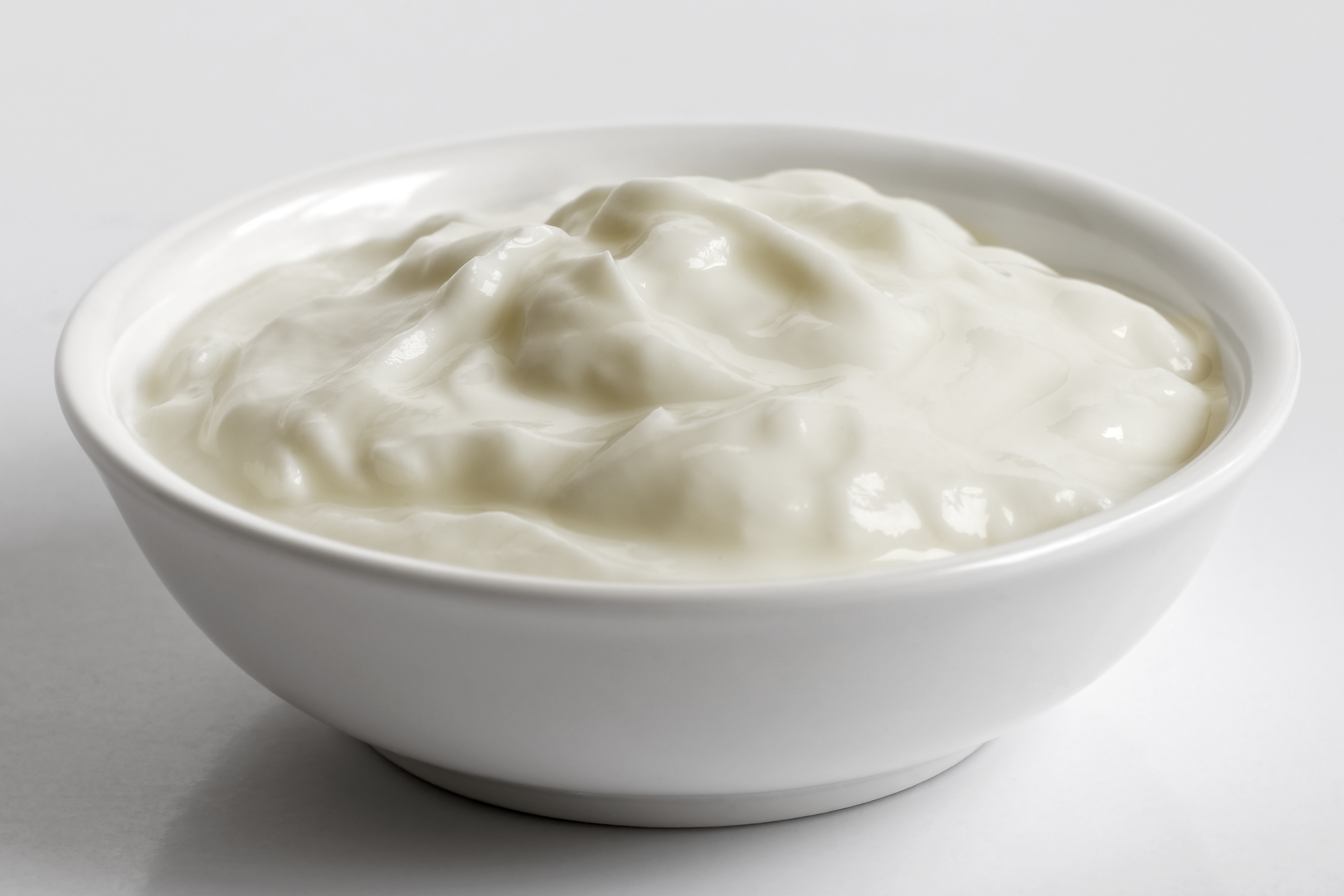 White ceramic bowl of skyr yoghurt isolated on grey background.