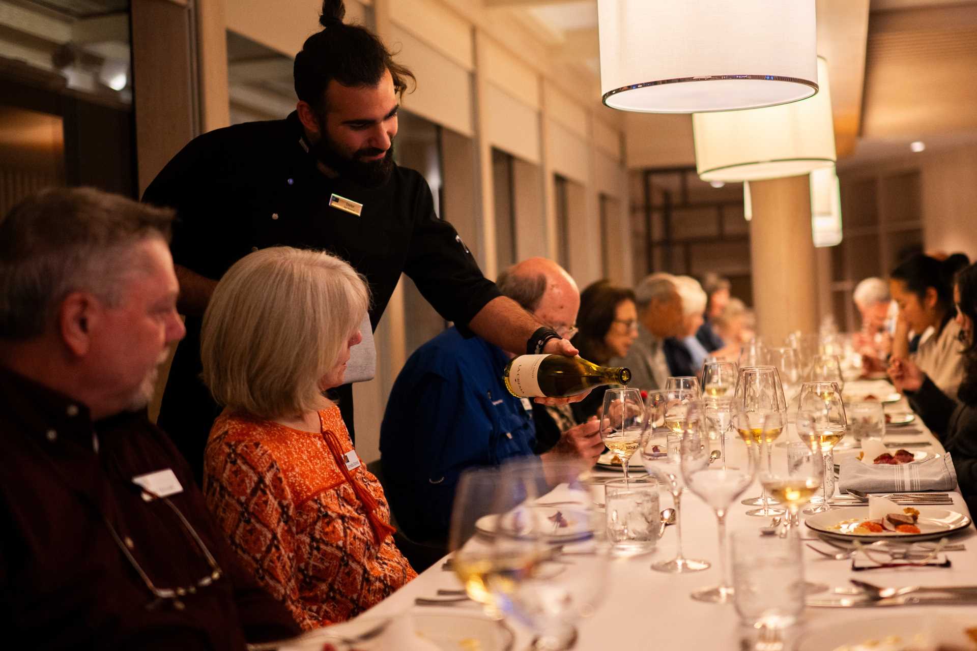 A staff member pours wine at dinner on board National Geographic Resolution