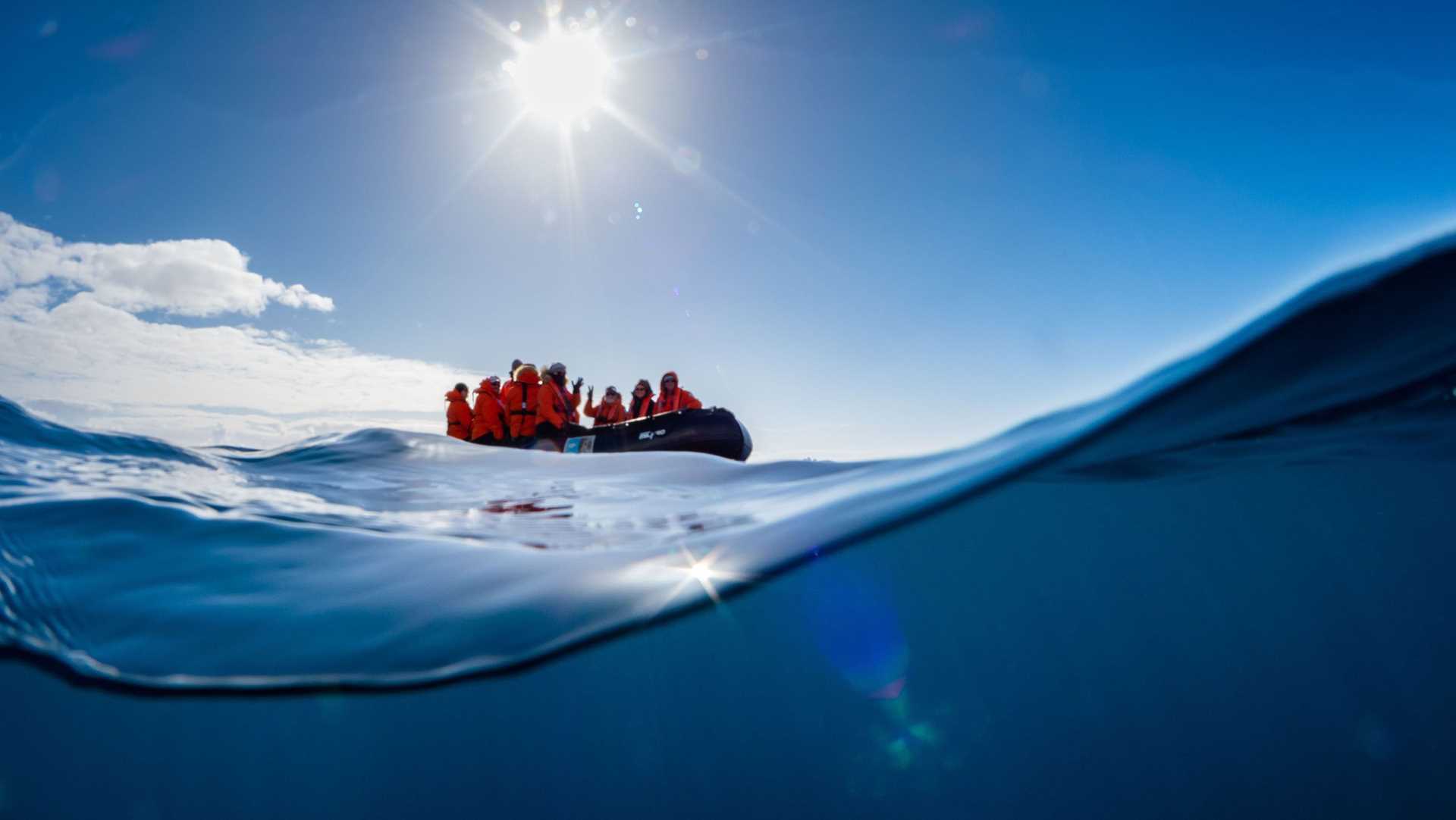 people in a zodiac, shot from underneath the water's surface