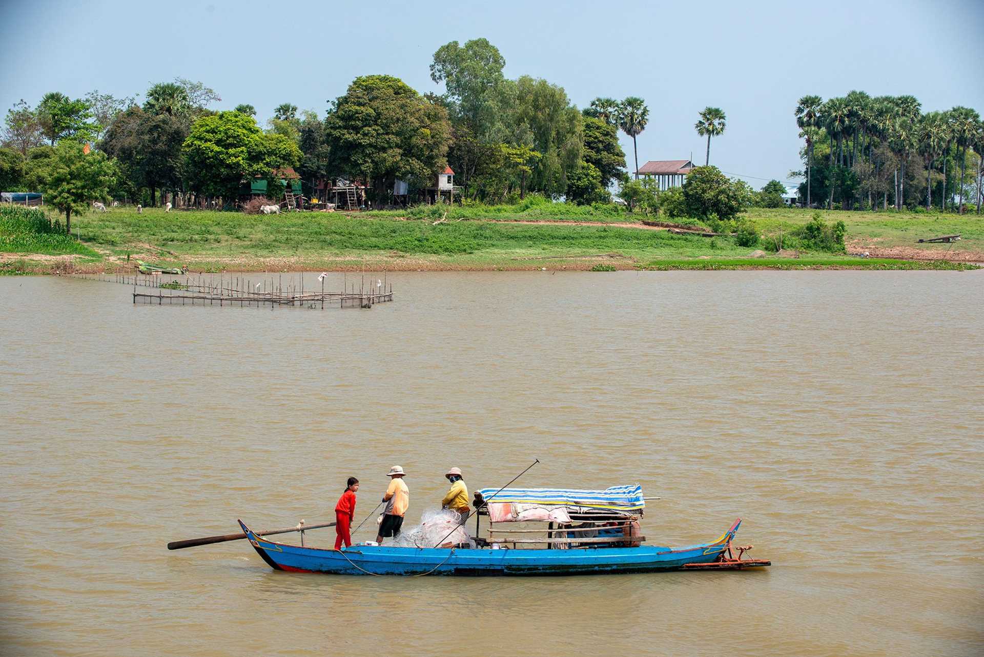 blue fishing boat on a large brown river