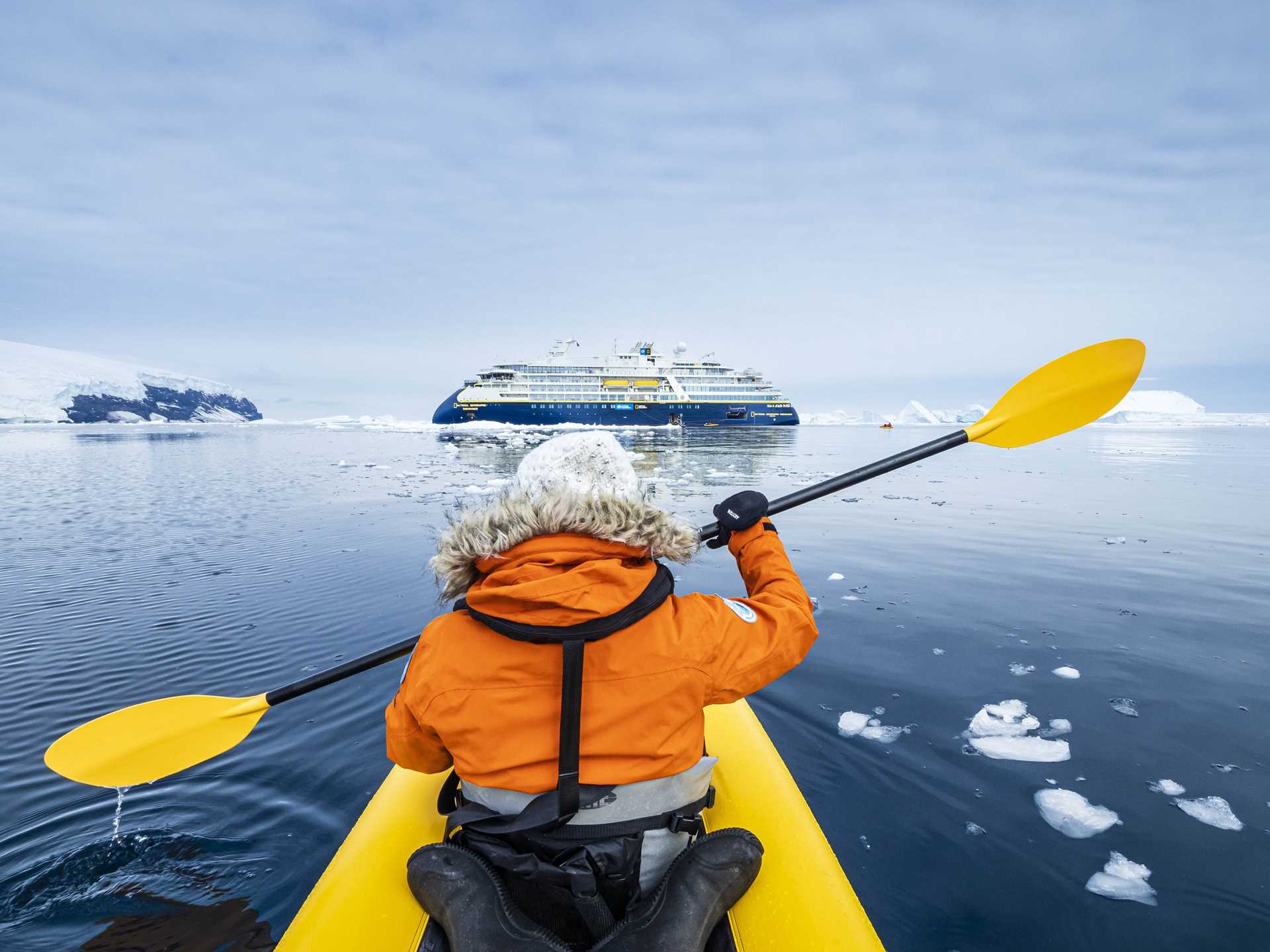 A guest kayaks in Antarctica with National Geographic Endurance in the background