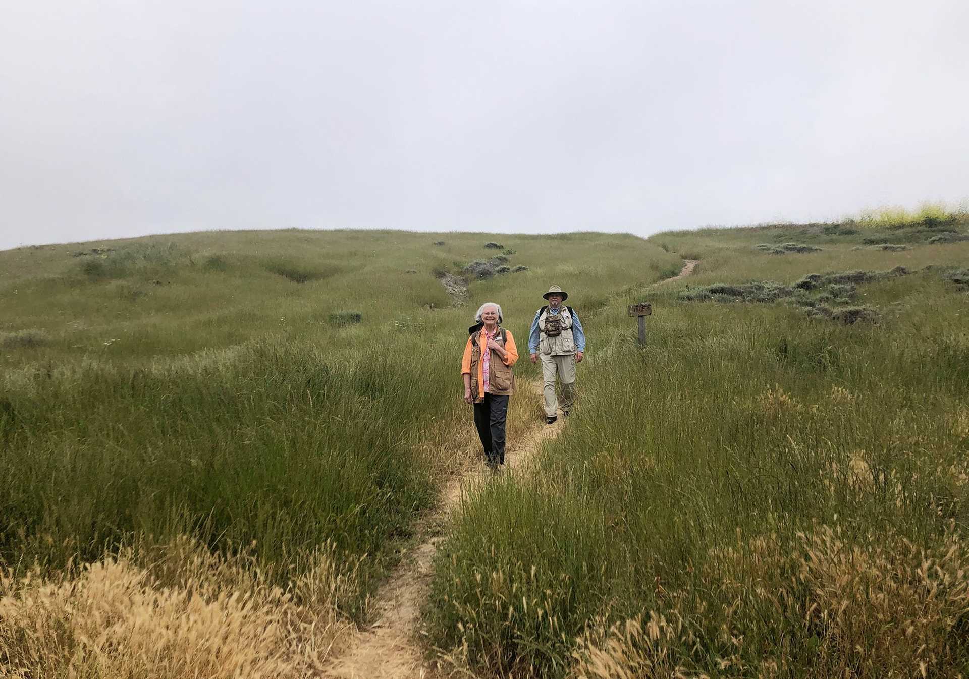 two people hiking on a hillside