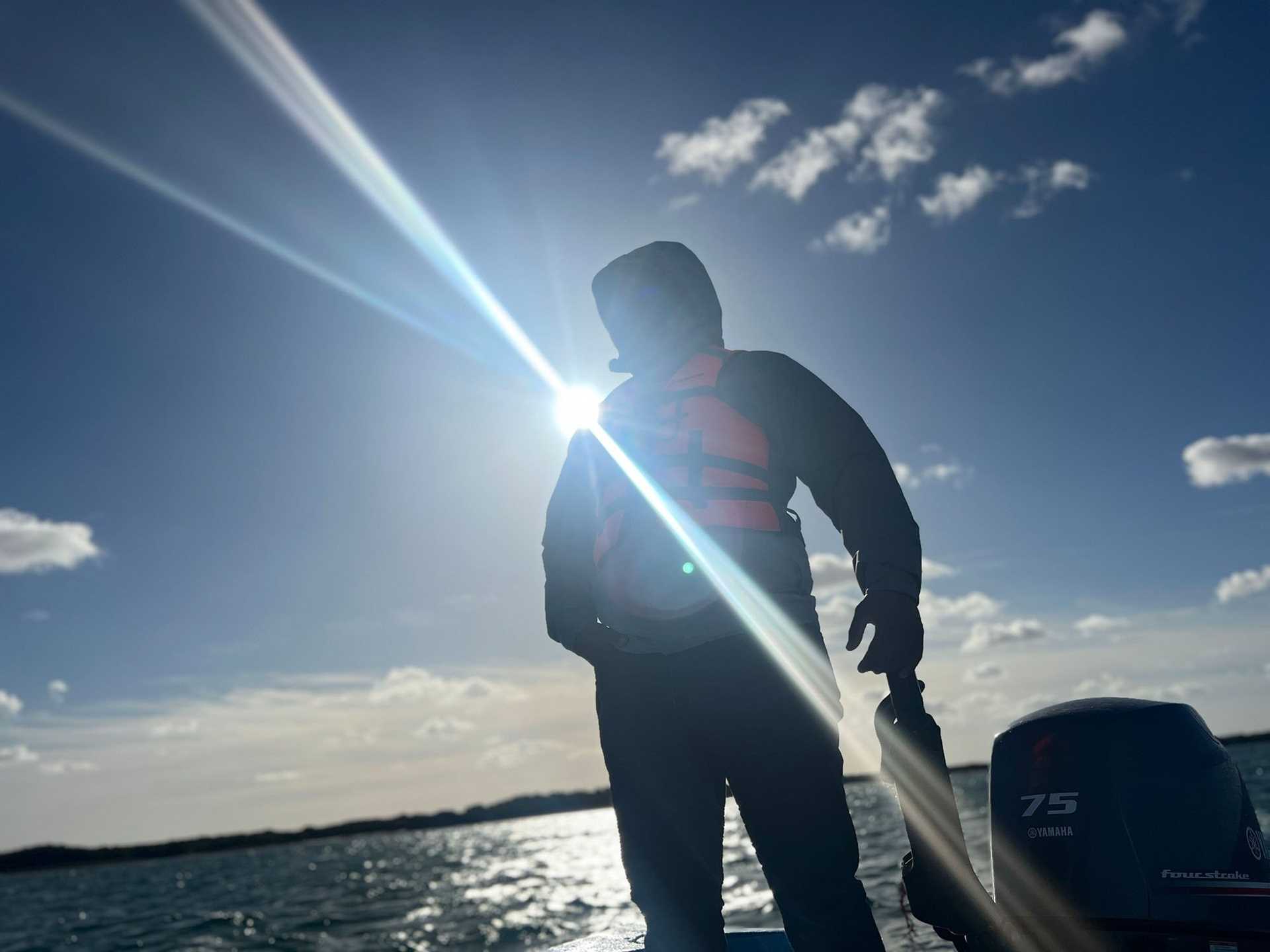 silhouette of a man driving a small boat