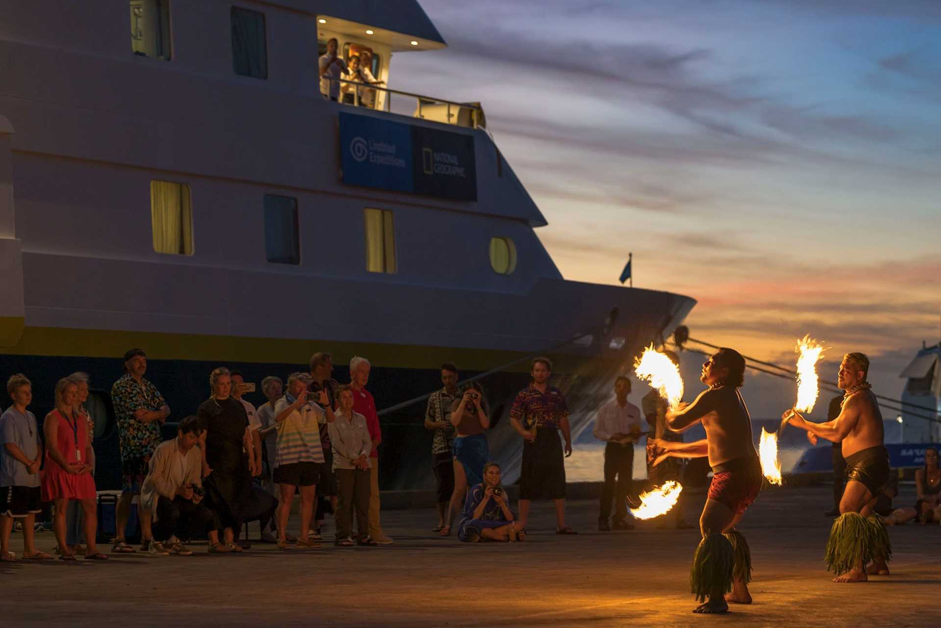 fire dancers perform with National Geographic Orion in the background
